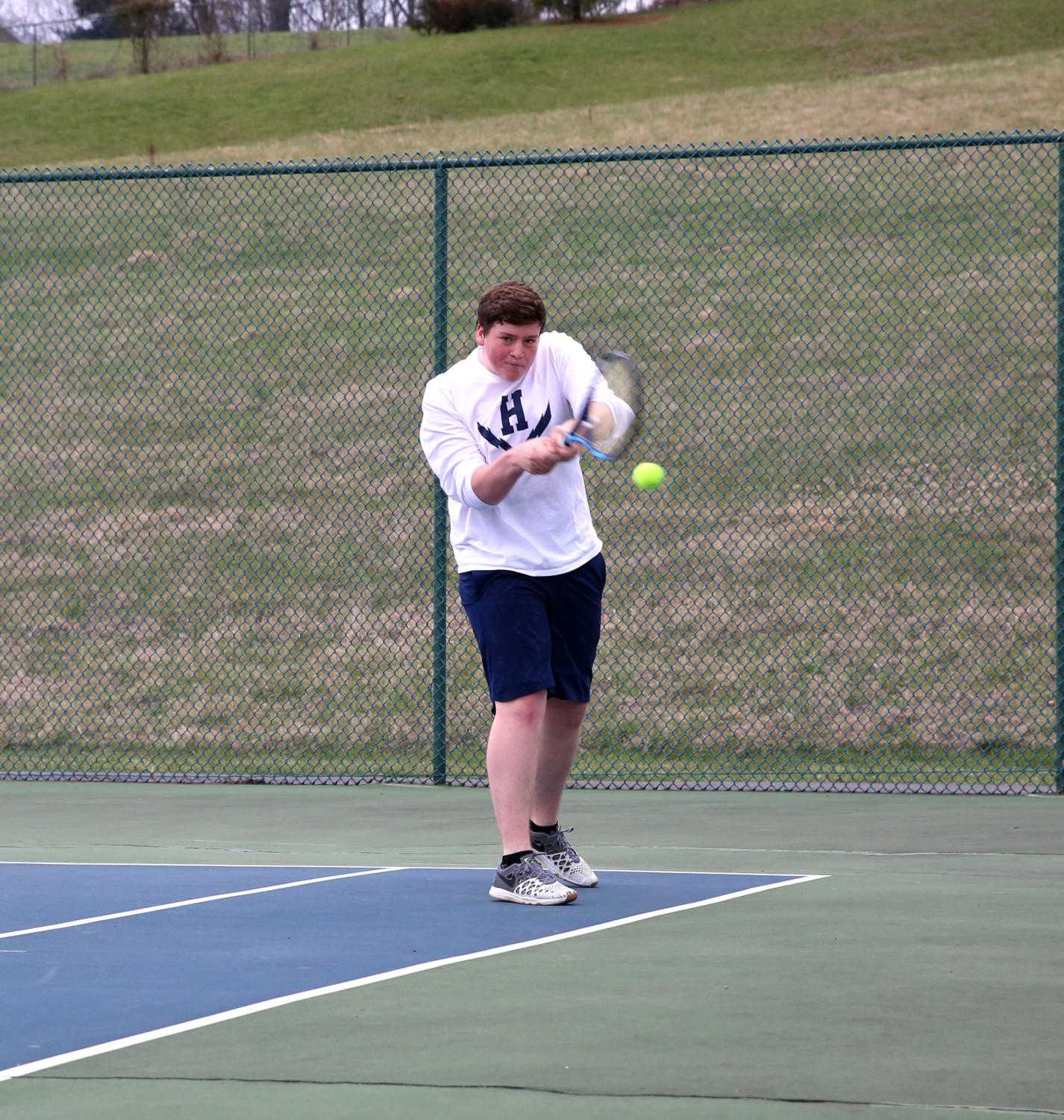 Junior Tobias Yoder steps up and returns a low shot from Turner Ashby's Canon Secord during his doubles match.